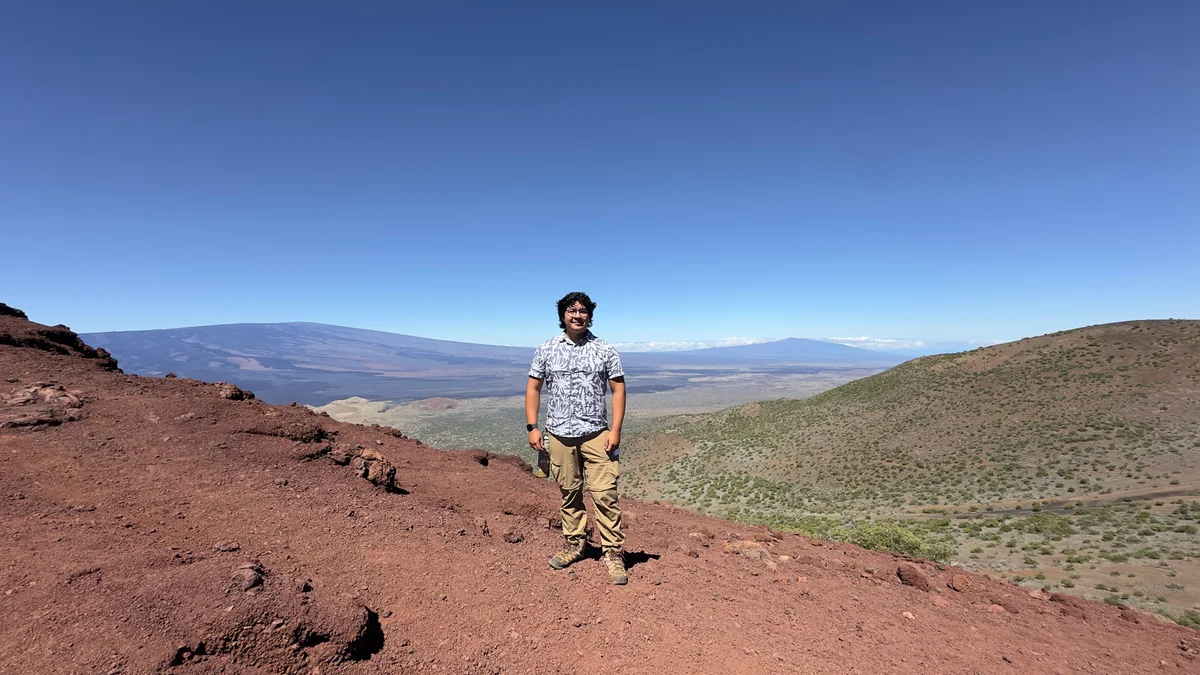 Joel Sotelo Flores standing on the volcanic landscape of Mauna Loa.