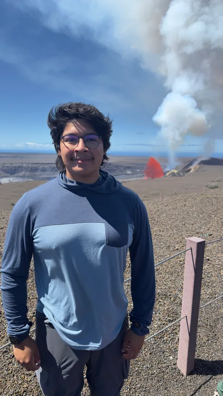 Joel Sotelo Flores standing in front of the Kīlauea volcanic landscape.